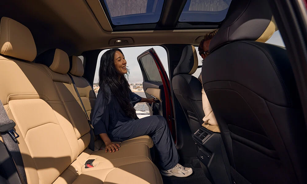 Vue des sièges arrière du Mazda CX-5 à partir de la portière côté passager, avec une femme qui entre du côté conducteur.